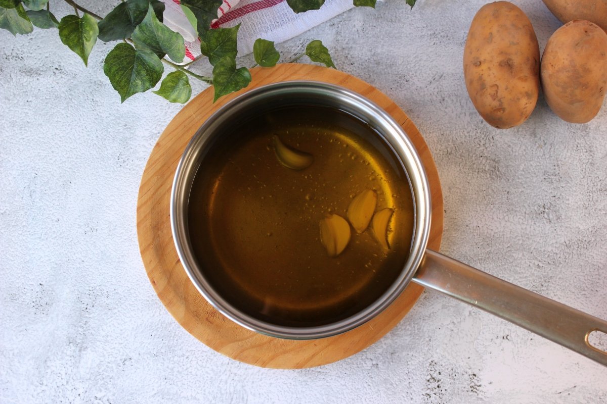 Dientes de ajo sumergidos en aceite de oliva virgen extra para ser confitados *